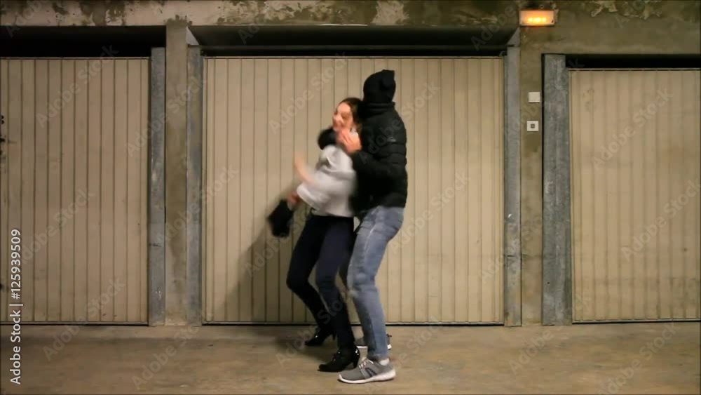 Homme attaquant une femme dans un parking. La fille utilise des techniques d'autodéfense pour se protèger