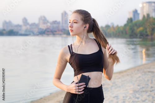Young woman at lake listening to music on cell phone