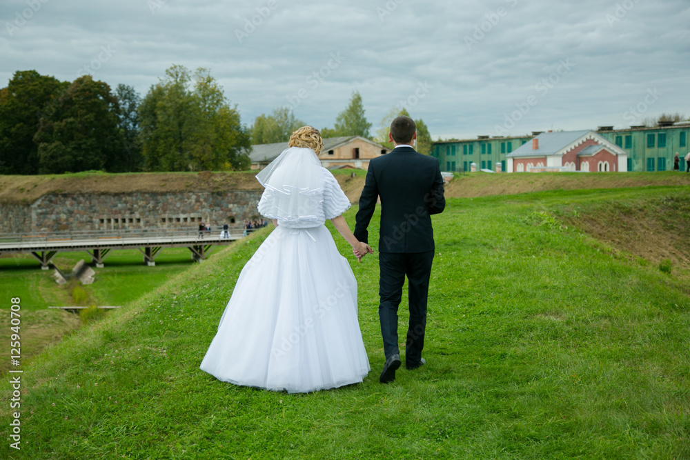 Fototapeta premium Happy bride and groom walking from back