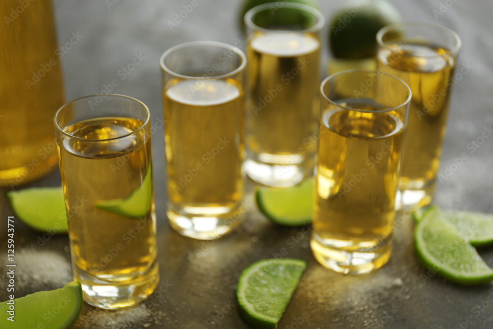 Gold tequila shots with lime and salt on gray table Gold tequila shots with lime and salt on gray table