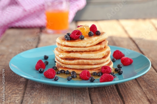 Plate full of tasty pancakes with berries and honey