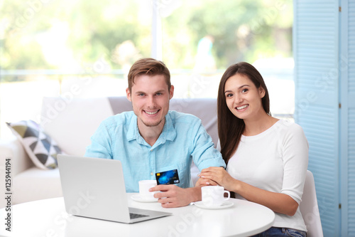 Happy couple sitting at table and making online shopping