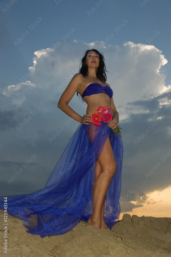 Beautiful adult woman in bikini and with pareo on the beach by t