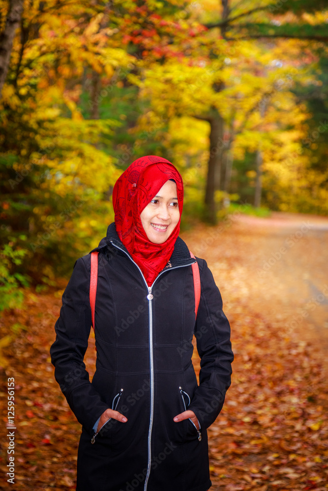 Muslim woman in North America during autumn with colorful maple leaf as background Muslim woman in North America during autumn with colorful maple leaf as background