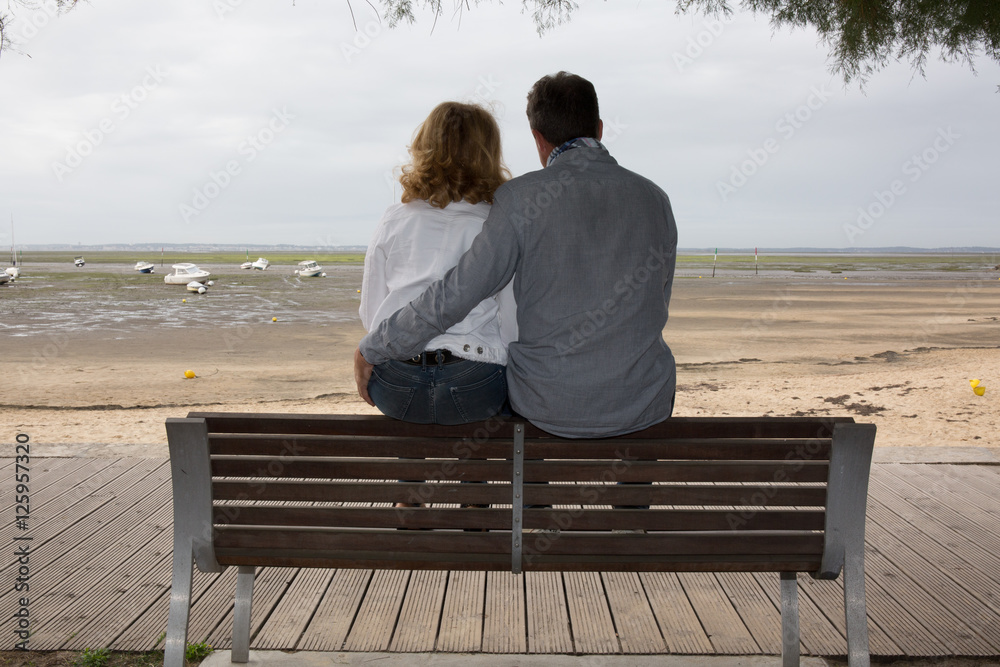 Couple sitting on the bench with the sea in background