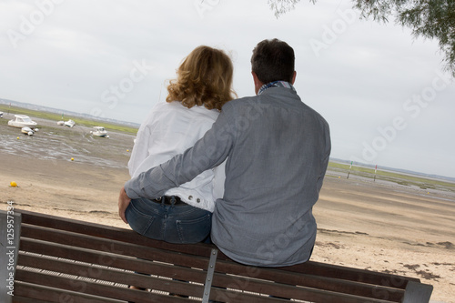 Back view of a couplehugging and watching sea on the beach