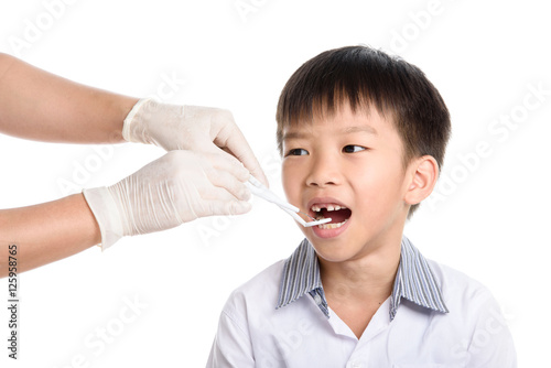 Dentist checking young asian boy teeth