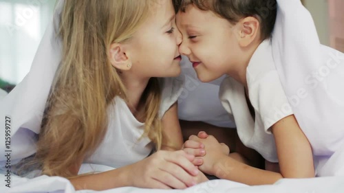 Lovely brother and sister lying in bed at home. Concept of Brother And Sister Together Forever 