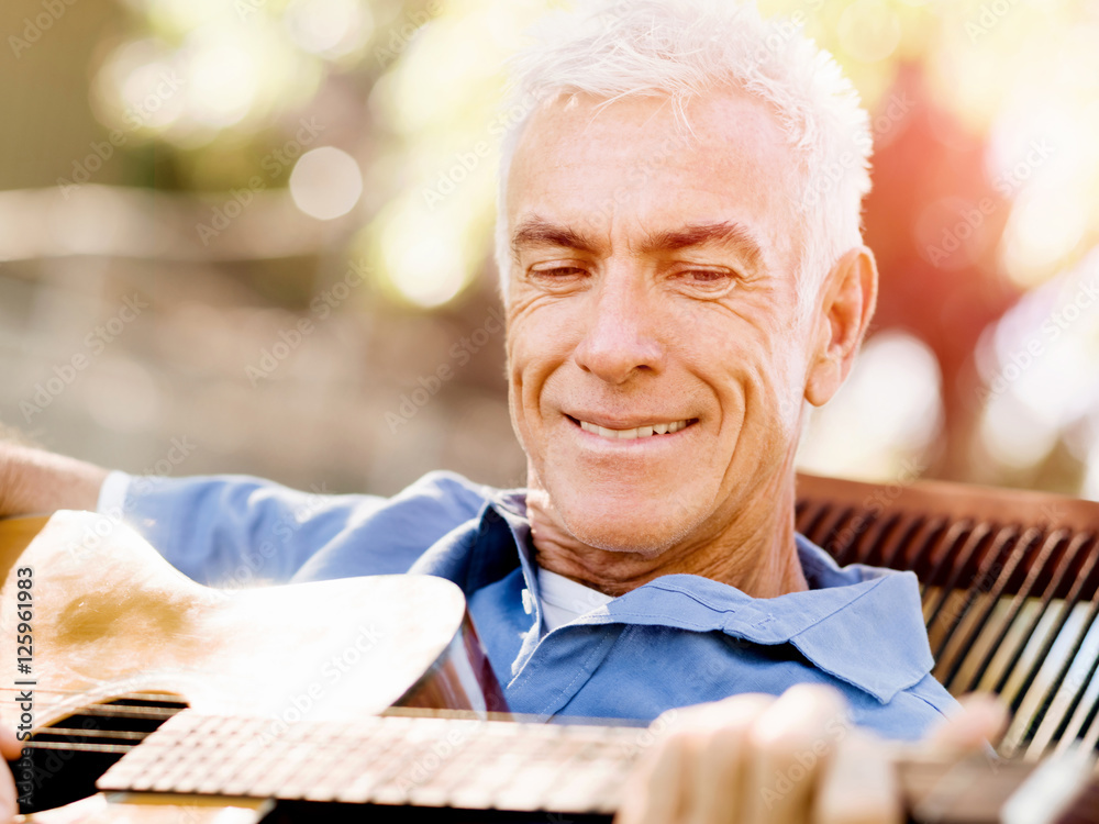 Senior man plying guitar outdoors Senior man plying guitar outdoors