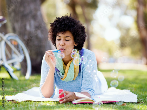 Beautiful woman blowing bubbles in park