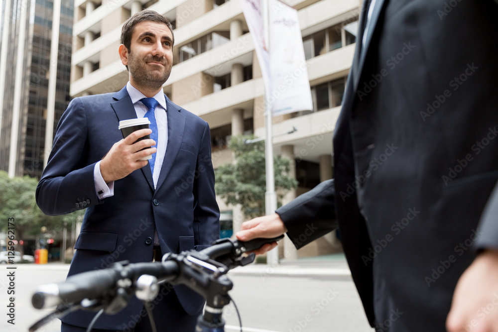 Two young businessmen with a bike in city centre Two young businessmen with a bike in city centre