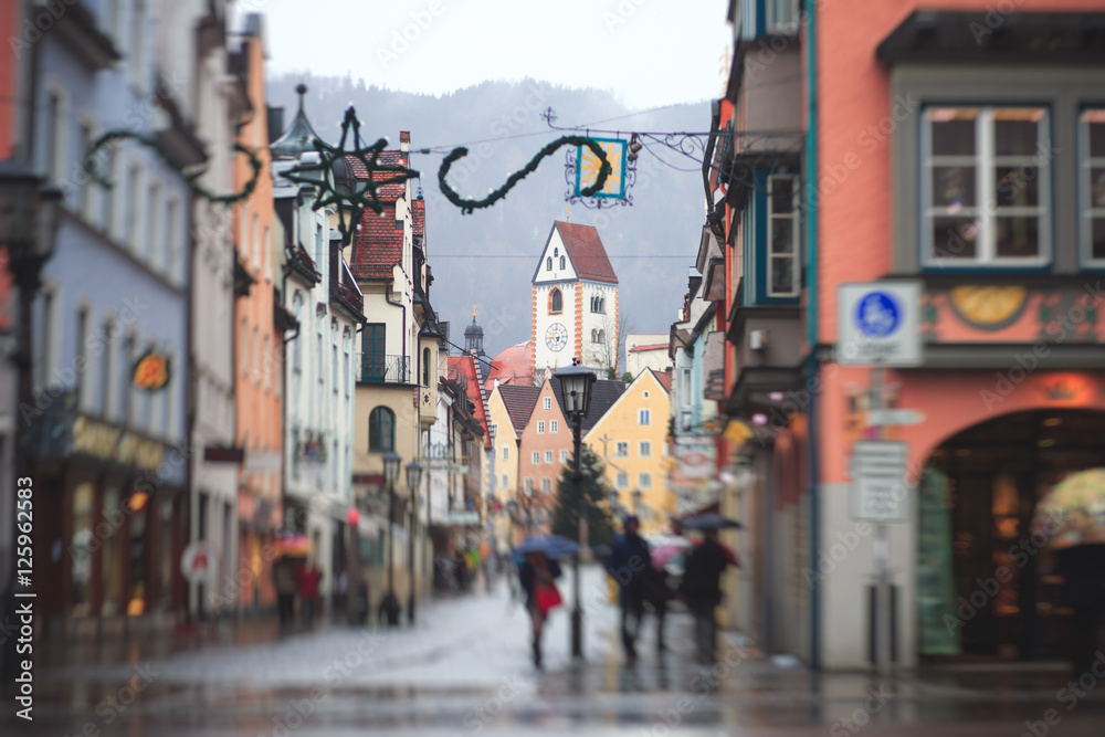 Beautiful vibrant multicolored downtown picture of street in Fussen, Bayern, Bavaria, Germany, with tourists and people walking near shop-windows and restaurants, houses in bavarian style