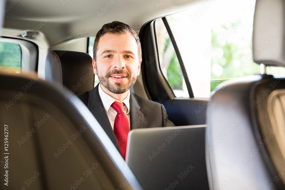 Hispanic man working while riding a car