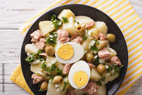 Spanish salad Patatas Alinadas of boiled potatoes with tuna, egg and olives close-up. horizontal top view photo