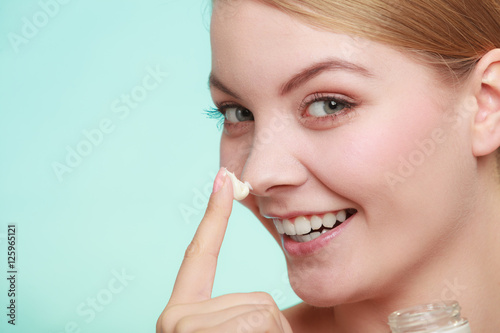 woman applying cream on her skin face.