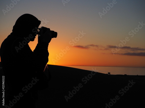 Man with camera at sunrise in dunes of Maspalomas Gran Canaria