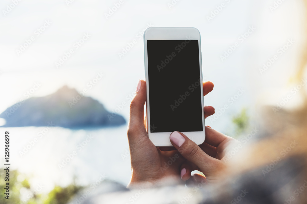 Hipster girl texting message on smartphone mobile closeup, view tourist hands using gadget phone on travel on background green mountains and sky landscape; finger touch screen cellphone mockup nature