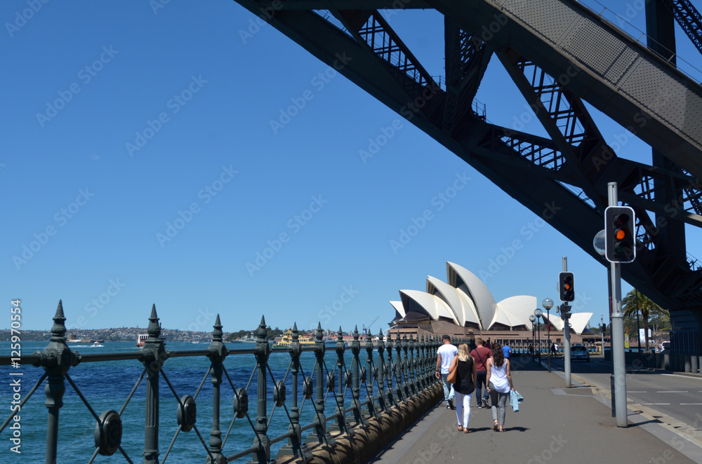 People walks under Sydney Harbour Bridge towards Sydney Opera Ho