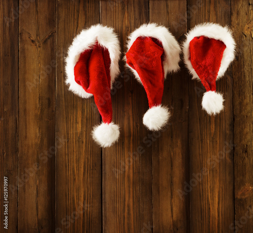 Christmas Santa Claus Hats Hanging Xmas Family Clothing on Wood Wall photo