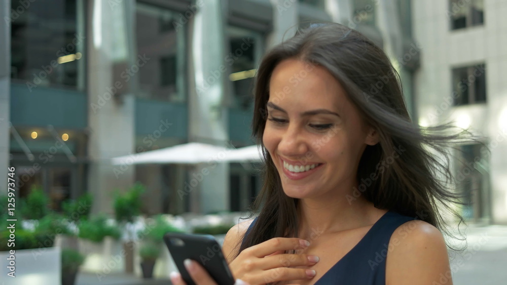 Attractive business woman commuter using smartphone walking in city