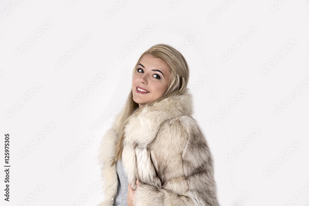 the young woman in a fur coat stands and smiles the young woman in a fur coat stands and smiles