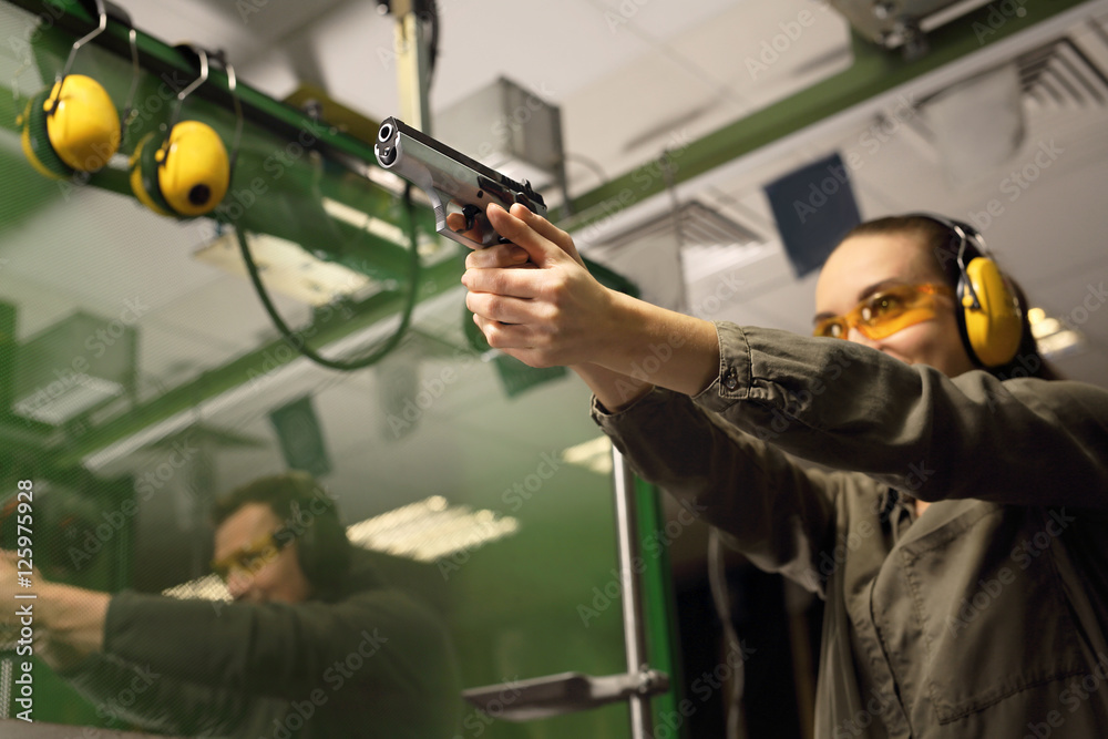 Obraz premium Samoobrona, kobieta na strzelnicy. Kobieta celuje do tarczy z pistoletu