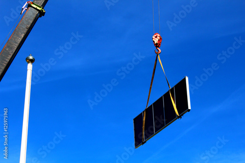 Crane lifting a large solar collector photo