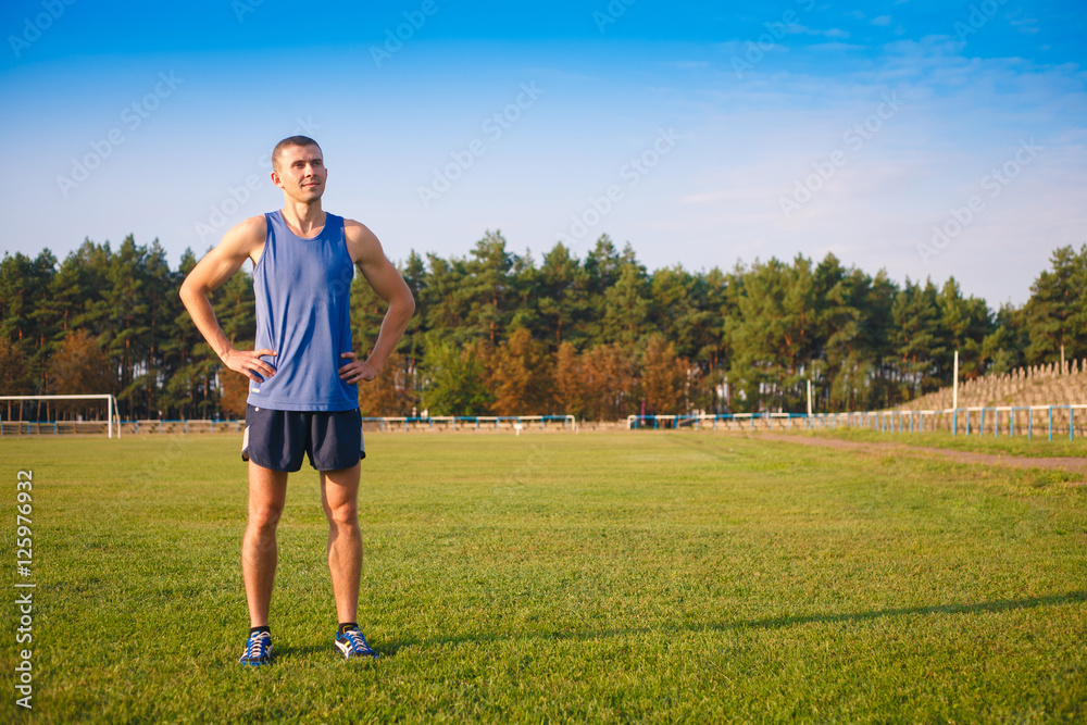 Young athletic man standing at the stadium. Young athletic man standing at the stadium.