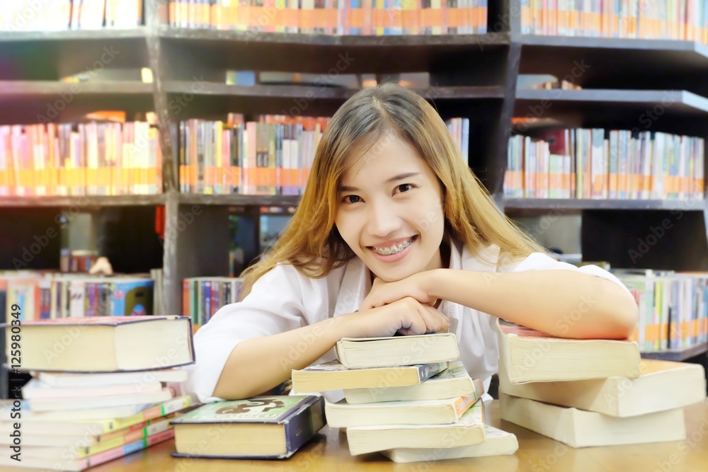 Portrait of a young student reading a book in a library. Portrait of a young student reading a book in a library.