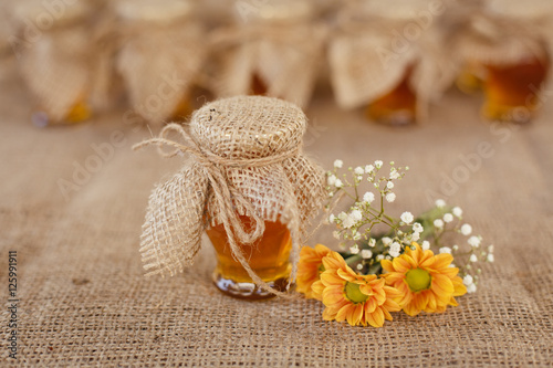 Jars with honey and orange flowers on a sacking background photo