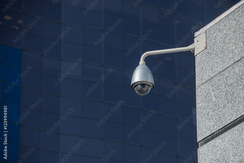 Modern security camera over office building background Modern security camera over office building background