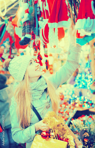 Beautiful young woman choosing Christmas decoration at market