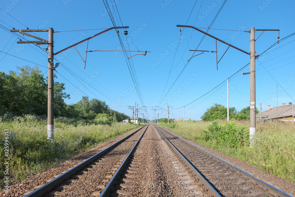 Double-track railway on a summer morning with the contact lines in rural areas Double-track railway on a summer morning with the contact lines in rural areas