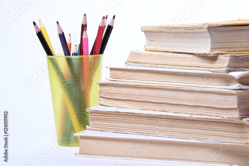 stack of old books. pencils in a glass