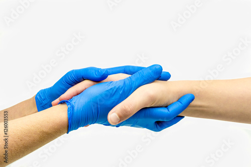 Caring hands with blue medical gloves giving comfort and holding hands.