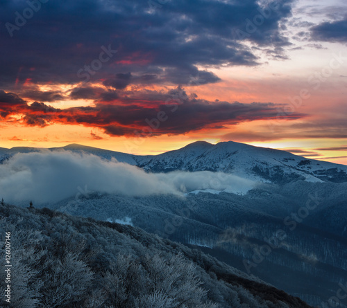 Beautiful landscape in the winter mountains at sunrise. Dramatic colorful sky. View of snow-covered hills.