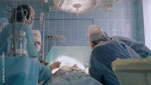 Hospital medical team wearing surgical clothing performing surgery using sterilized equipment