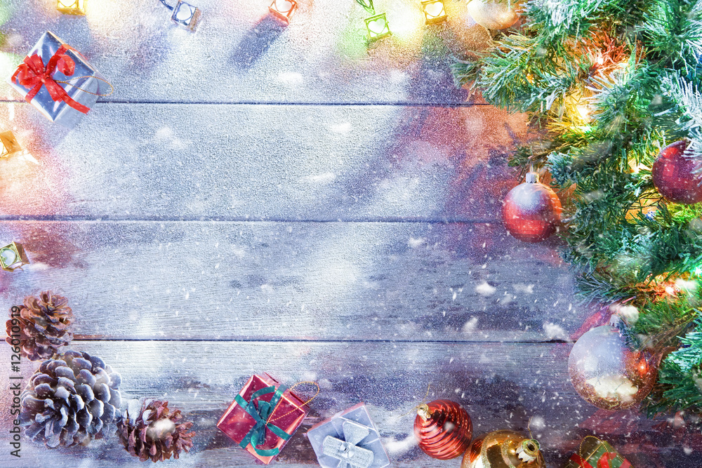 view  of lit Christmas tree  and gift boxes on snowbound  wooden back