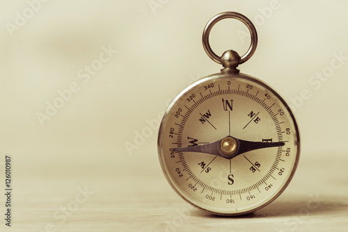 Old compass on a light yellow background