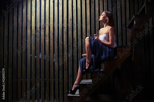 Inspired woman with naked lean legs posing on wooden stairs in d