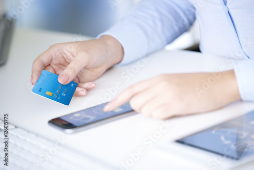 Cuadro en lienzo Close-up shot of a young businesswoman holding bank card in her hand while using smartphone app to log in her bank account