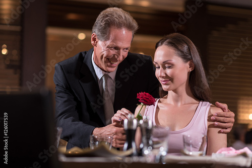 Smiling positive man giving a rose to the woman