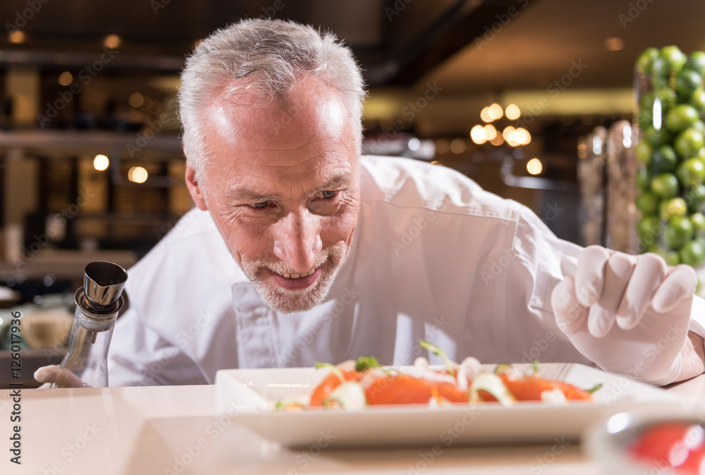 Delighted chef making the last corrections of his dish Delighted chef making the last corrections of his dish