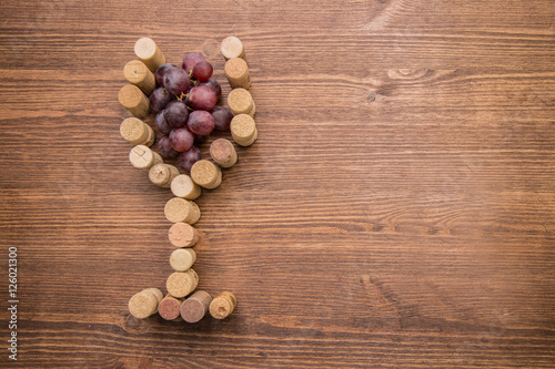 Glass made with cork wine and grapes inside on wood background