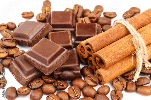Dark chocolate bar, cubes, cinnamon sticks and coffee beans isolated on white background.