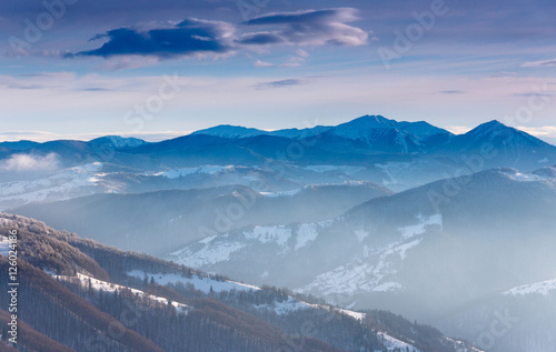 Winter morning landscape in mountain. View on snow-covered hills and trees.