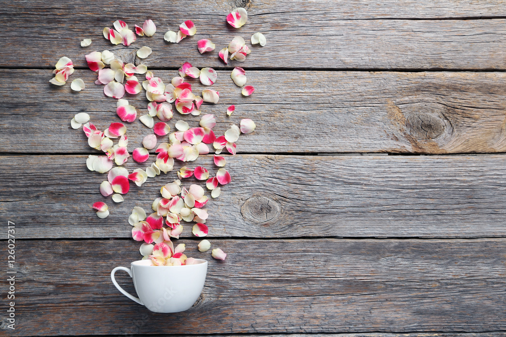 Rose petals in white cup on grey wooden table