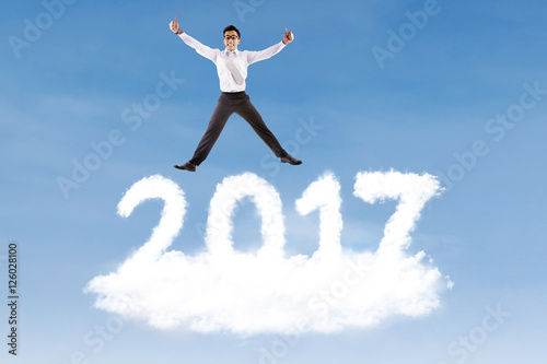 Businessman leaping above cloud shaped number 2017