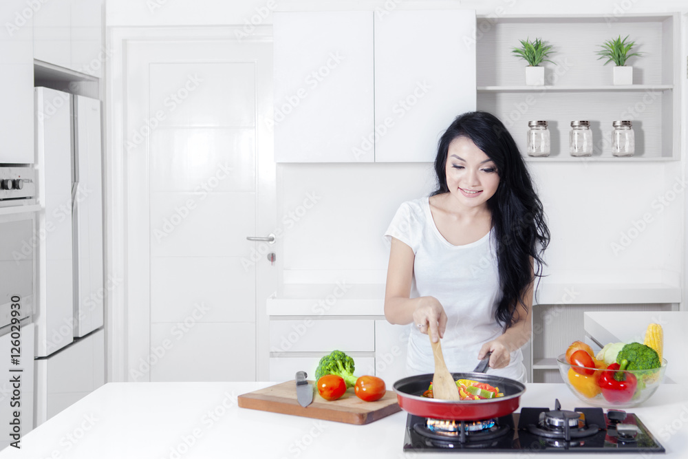 Pretty Asian woman cooking on stove