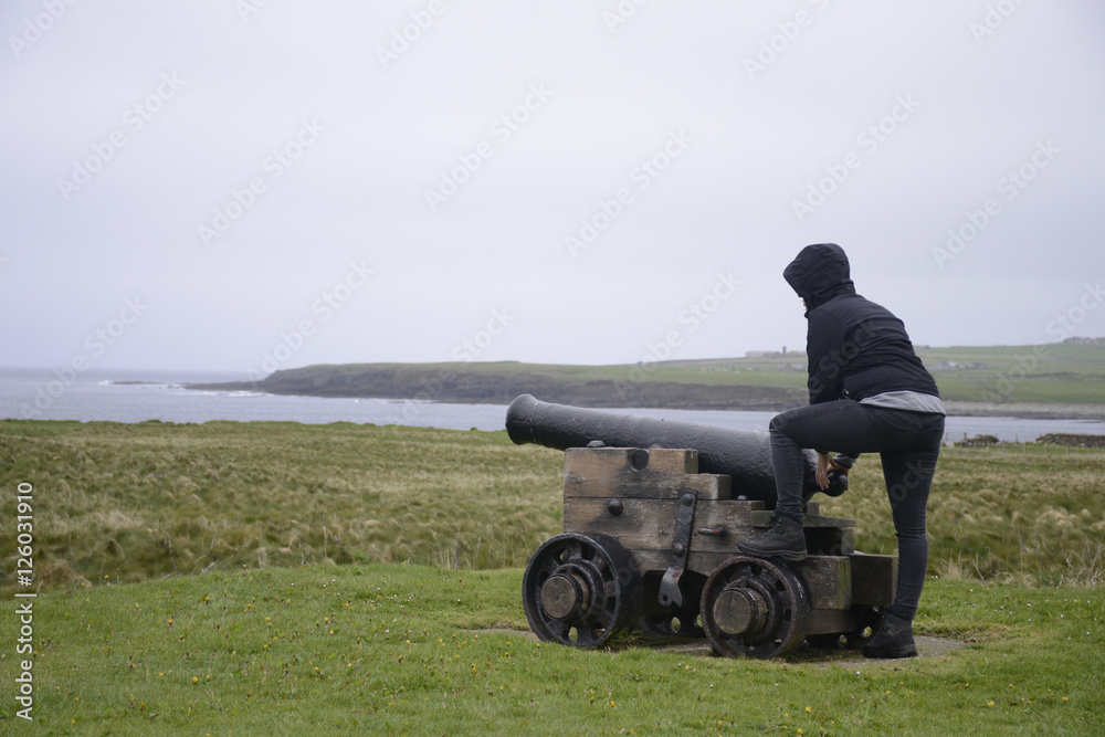 Obraz premium Girl shooting cannon Orkney coastline cliff landscape